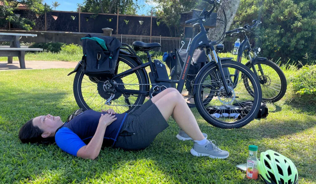 Karen resting in the shade with the e-bikes